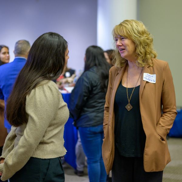 Two women engaged in conversation at an indoor networking event.