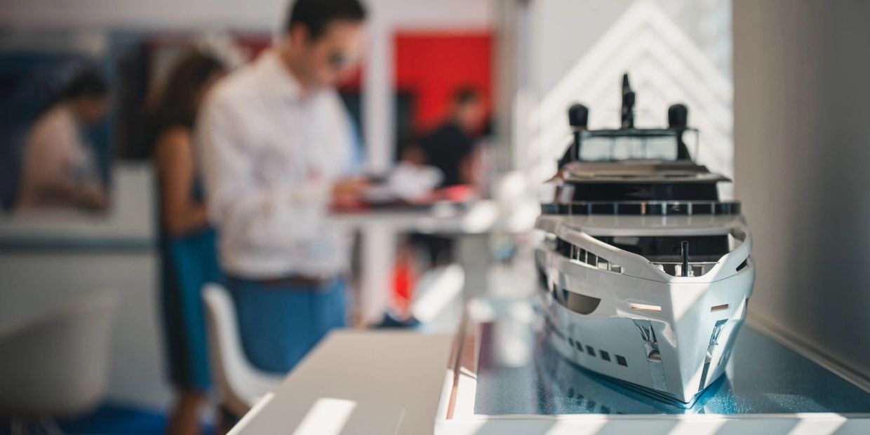 Model yacht on display in front of blurred people.