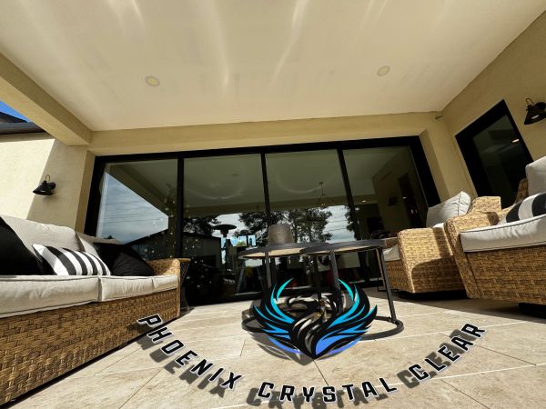 Modern outdoor patio area with wicker furniture and large glass doors.