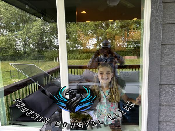 Smiling girl behind a window with Phoenix Crystal Clear logo.