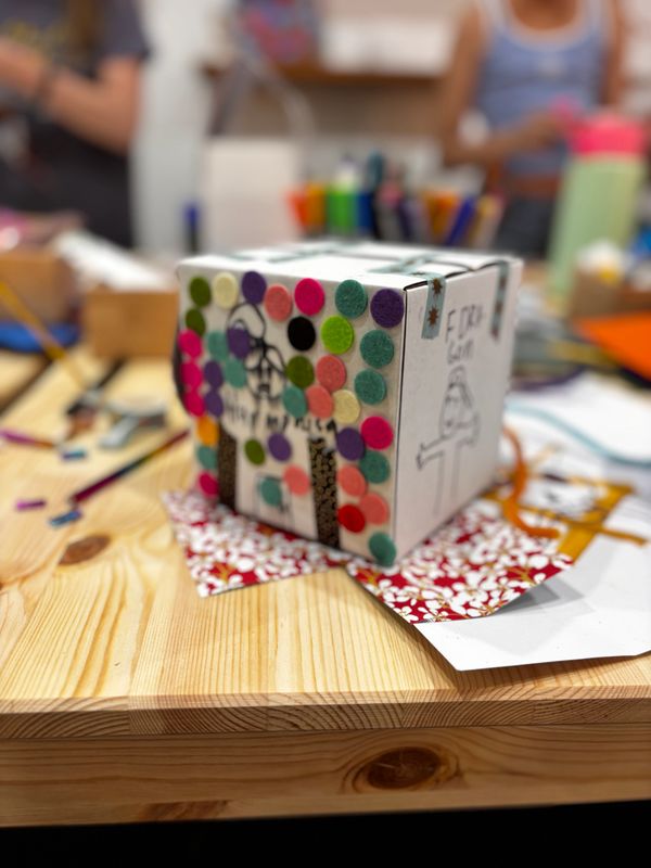 A decorated craft box with colorful felt dots on a wooden table.