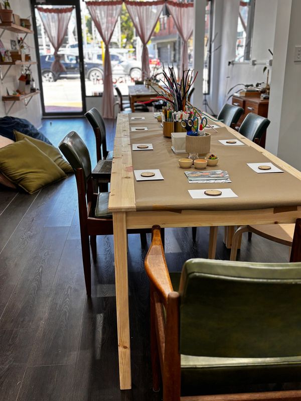 A long table set up with craft supplies in a bright room.