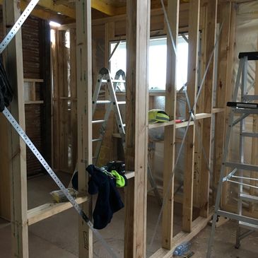 Interior of a house under construction with wooden framing and ladders.