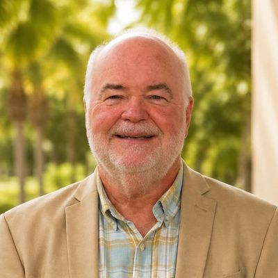 Smiling elderly man outdoors in a beige blazer.
