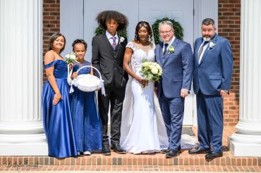 Wedding group photo with bride, groom, and attendants in formal attire.