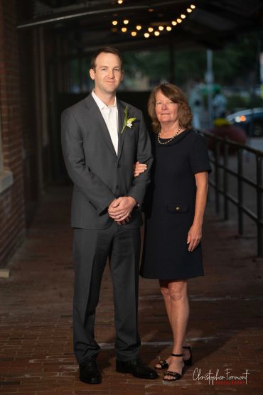 Man in suit with woman in black dress posing outdoors.