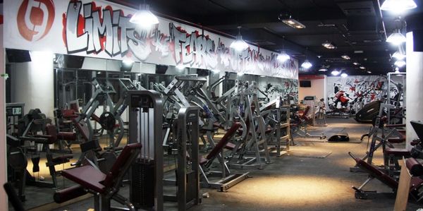 Modern gym with various weight machines and motivational graffiti on the wall.