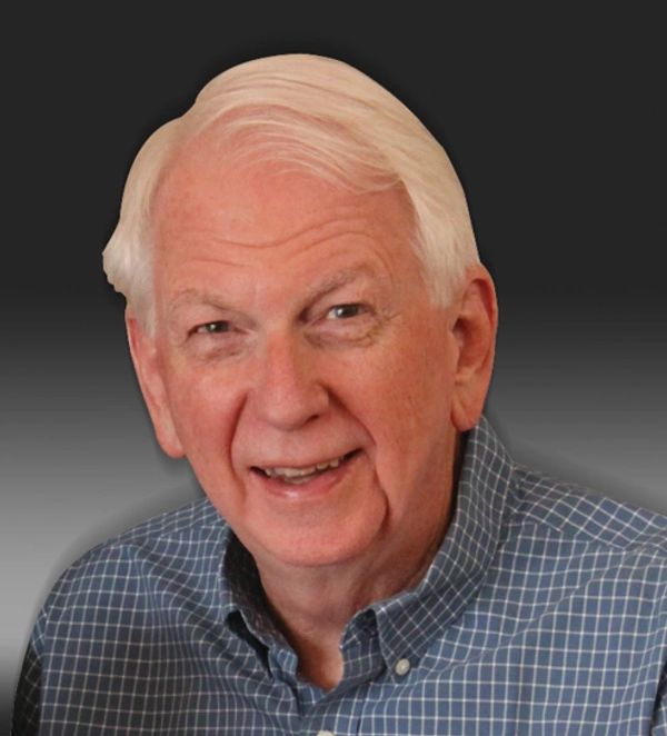 Smiling elderly man with white hair wearing a blue checkered shirt.