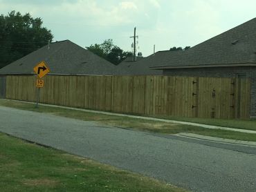 Wooden fence with a right turn road sign in a residential area.