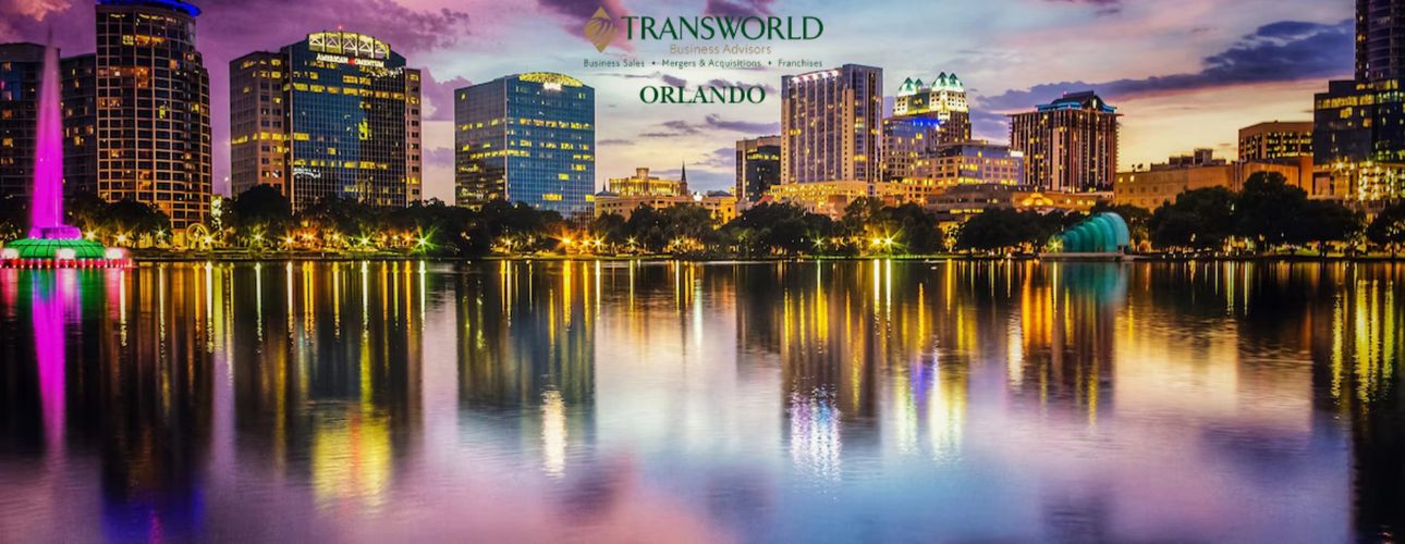 Orlando skyline at dusk with colorful reflections on the water and a Transworld Business Advisors logo.