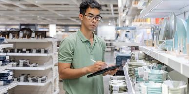 Man inspecting dishes in a store with a clipboard.