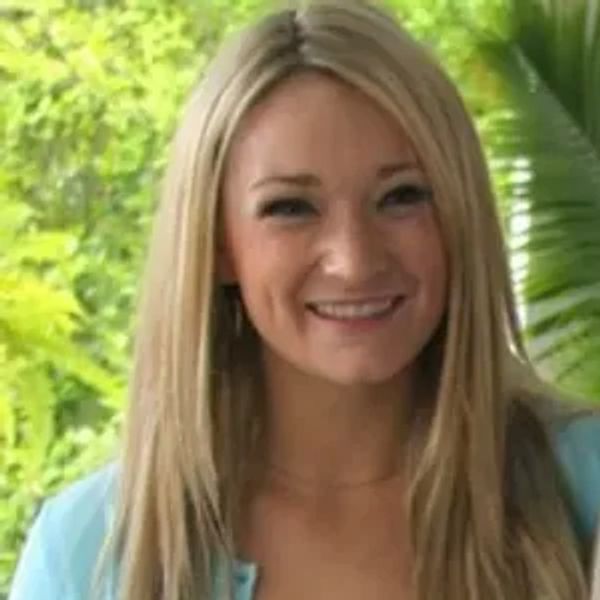 Smiling woman with long blonde hair outdoors.