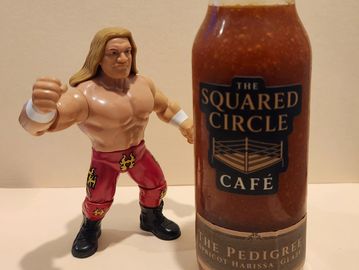 Wrestling action figure next to a jar of The Squared Circle Café sauce.