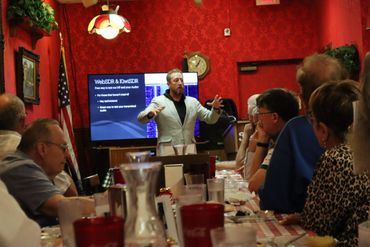 Man giving a presentation to a group in a red-walled room.