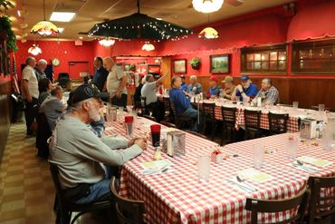 People dining in a cozy restaurant with red and white checkered tablecloths.