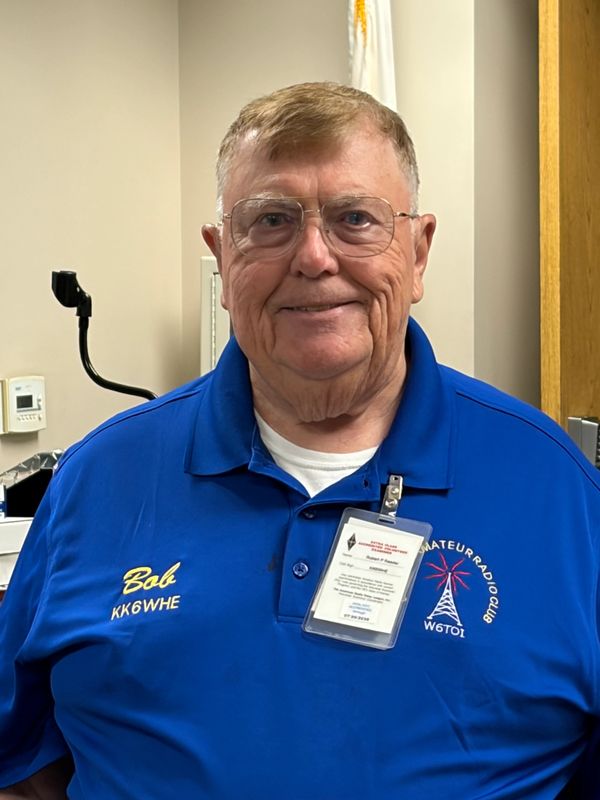 Older man named Bob in a blue Amateur Radio Club shirt with ID badge.