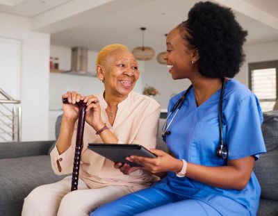 Nurse talking to elderly woman with cane.