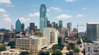 Downtown city skyline with tall buildings under a partly cloudy sky.