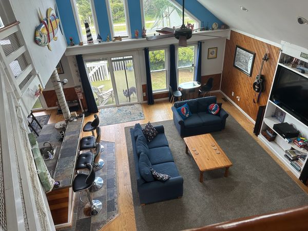 Cozy living room with blue sofas, wooden coffee table, and large window overlooking a garden.
