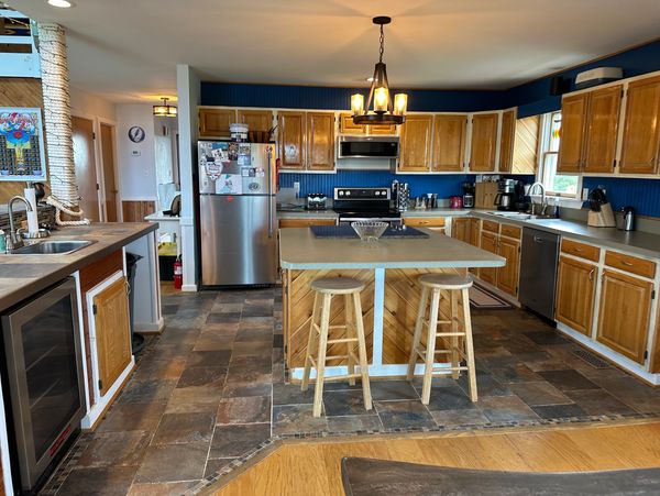 Spacious kitchen with wooden cabinets, central island, and modern appliances.