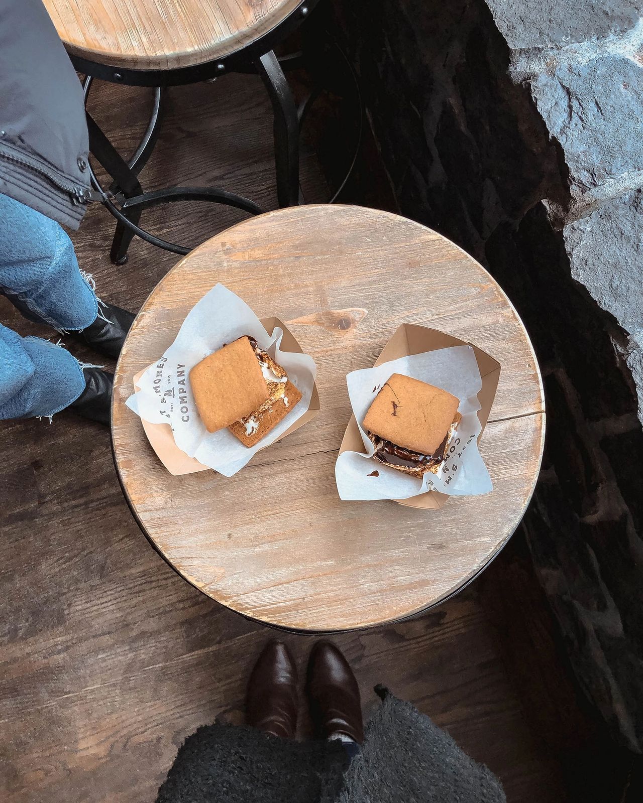  An overhead view of two handcrafted s’mores served on parchment paper at 1927 S’mores Company in downtown Portland, Oregon. The s’mores feature golden graham crackers, gooey marshmallows, and rich melted chocolate, placed on a rustic wooden table. This charming dessert spot evokes nostalgic summer camp vibes and is a must-visit for anyone with a sweet tooth exploring Portland. Photo by Nastasia Yakoub