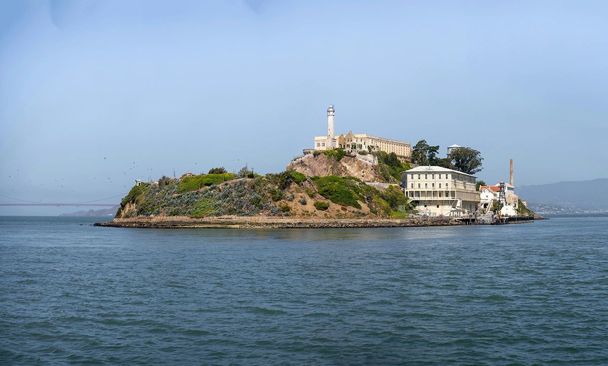 A scenic view of Alcatraz Island in San Francisco Bay, featuring the historic Alcatraz Federal Penitentiary surrounded by rugged cliffs and the waters of the bay. Famous for its notorious prison history and stunning panoramic views, Alcatraz is one of San Francisco’s most iconic landmarks and a must-visit destination for history lovers and travelers alike.
