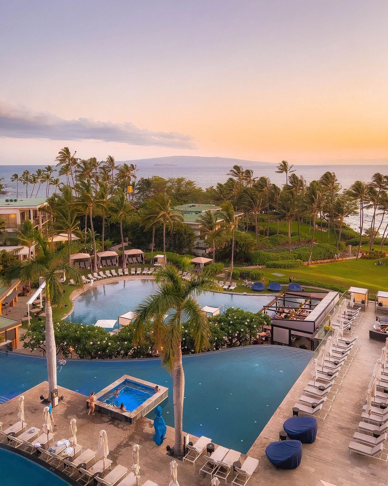 Aerial view of Andaz Maui at Wailea Resort pools, plumeria flowers, and ocean views at sunset