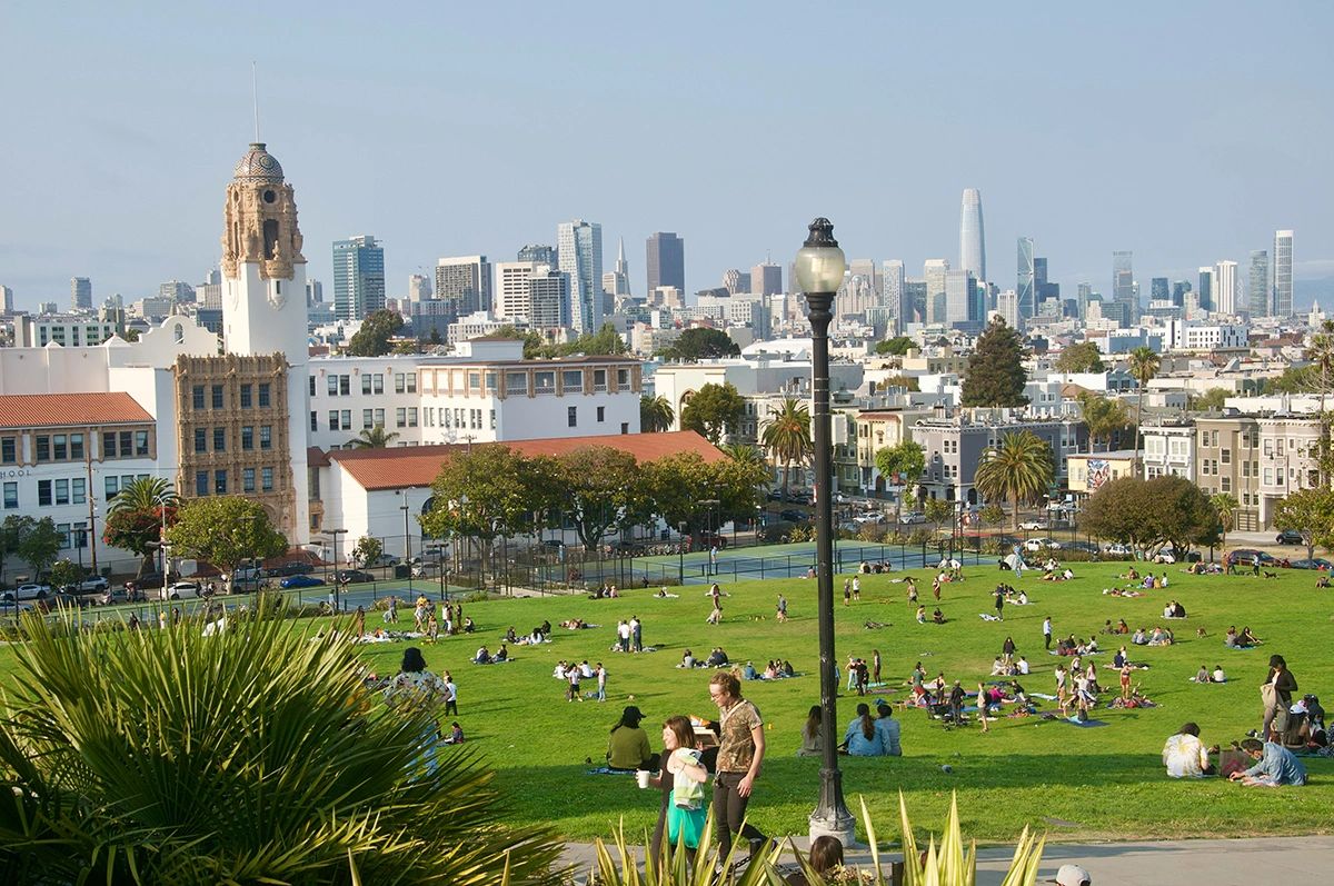A vibrant afternoon at Dolores Park in San Francisco, with locals relaxing on the grassy lawn and stunning views of the downtown skyline in the background. Known for its lively atmosphere, palm trees, and iconic cityscape, Dolores Park is one of the best places to experience the local vibe and enjoy panoramic views in San Francisco.