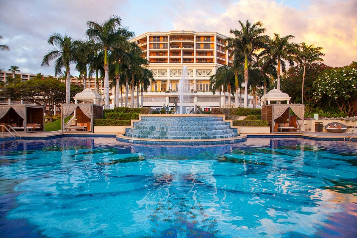 Multi-tiered pool with cascading waterfall and palm trees at Grand Wailea resort in Maui's Wailea area