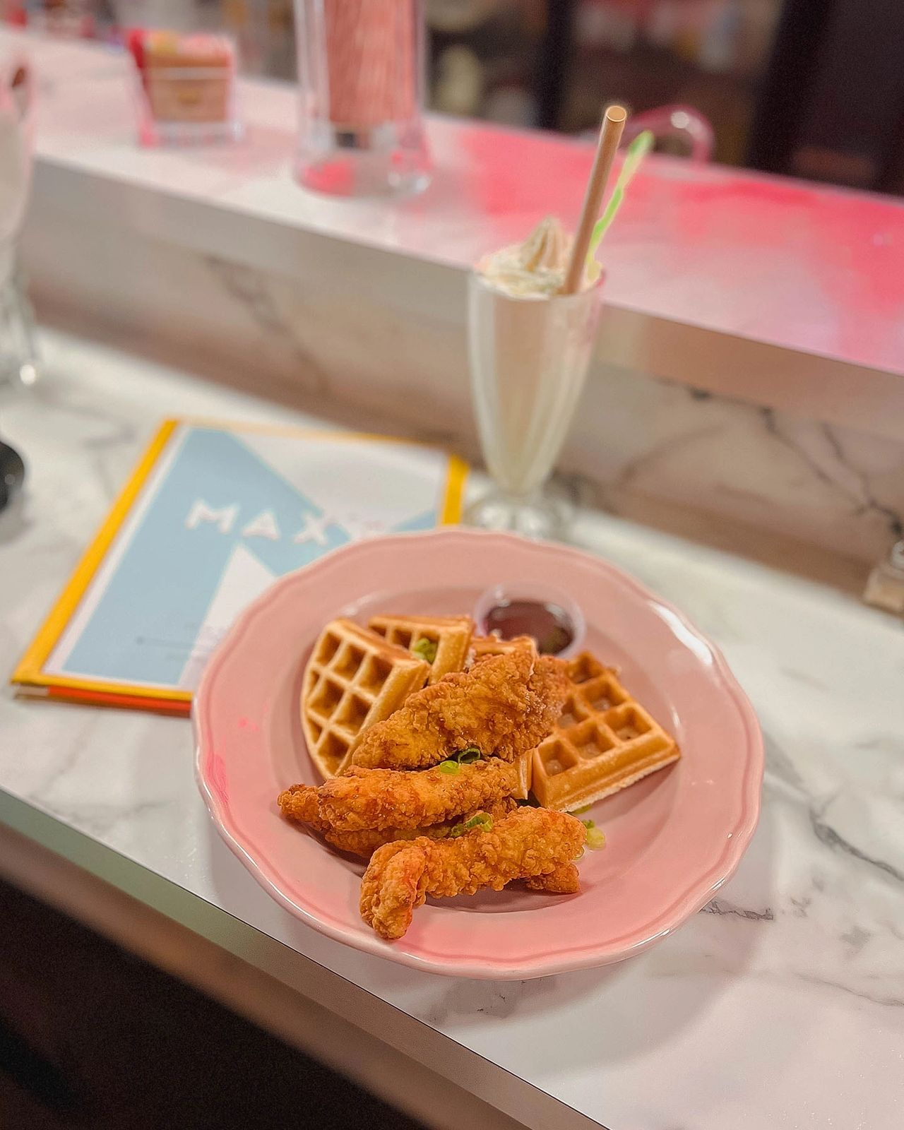 Craving the perfect mix of sweet and savory? Look no further than Max’s Eatery in Lancaster, PA, where their crispy fried chicken and fluffy waffles deliver the ultimate comfort food experience. Served on a pastel pink plate with a side of syrup and paired with a classic milkshake, this diner-style dish is a must-try for food lovers. Whether you're stopping by for brunch, lunch, or a late-night bite, Max’s Eatery is the place to indulge in delicious, nostalgic flavors with a fun, retro vibe.