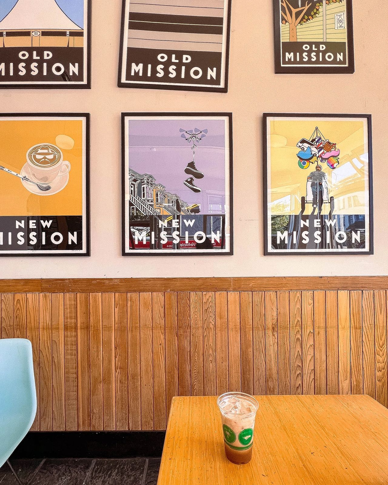 Inside Precita Park Café in San Francisco’s Mission District, featuring colorful "Old Mission" and "New Mission" artwork, wood-paneled walls, and a cozy setup with an iced coffee. A relaxed local favorite for casual coffee dates, quiet afternoons, and soaking up the artsy Mission District vibe.