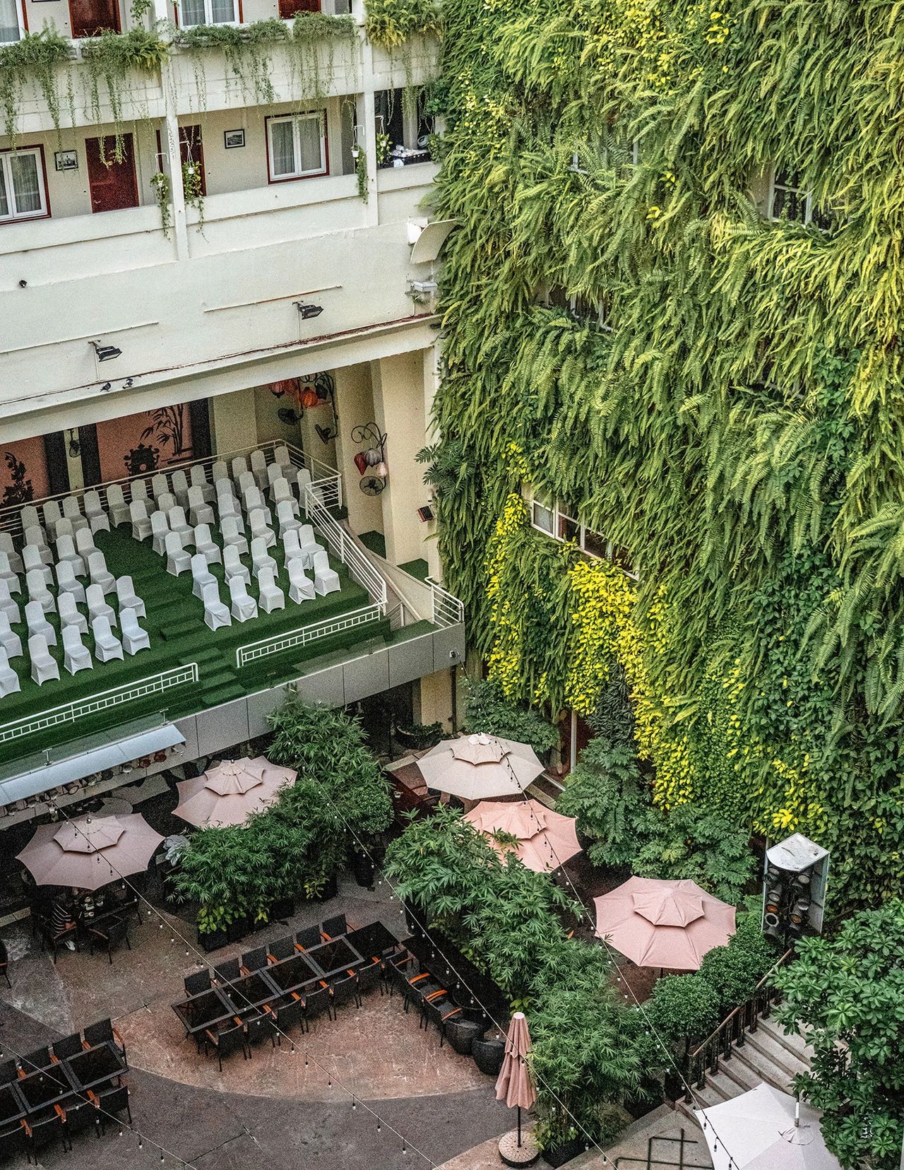 Rex Hotel's greenery-filled courtyard with cascading plants and pink umbrellas – a historic hotel featured in this Ho Chi Minh City guide