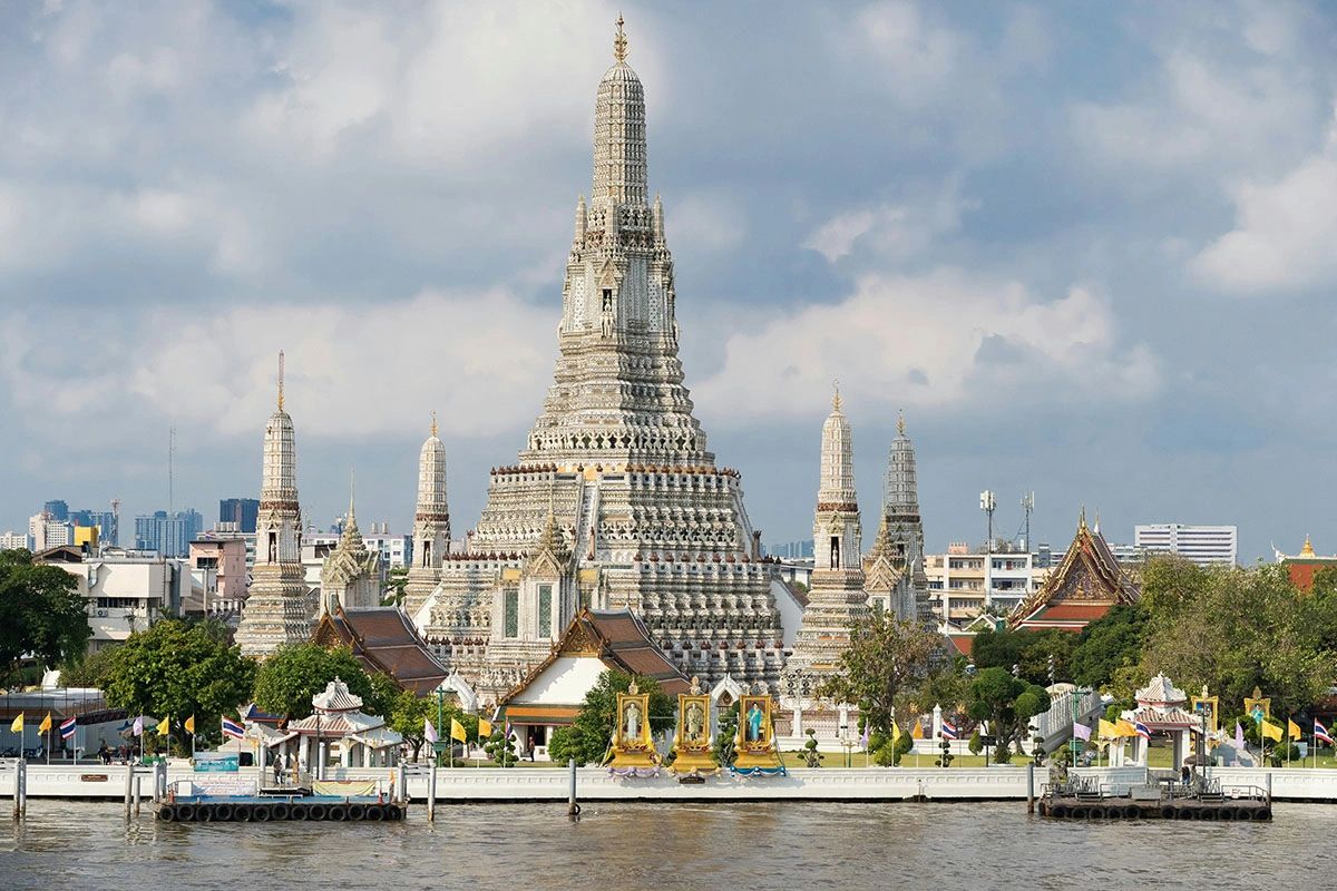 Wat Arun, also known as the Temple of Dawn, is one of Bangkok’s most iconic and visually stunning temples. Located on the banks of the Chao Phraya River, this magnificent structure is famous for its intricately designed spires covered in colorful porcelain and glass mosaics. Standing at 73 meters (240 feet) tall, the central prang offers breathtaking views of the city and river. Best visited at sunrise or sunset, Wat Arun lights up beautifully in the evening, making it a must-see attraction in Thailand. Whether you explore its rich history, Buddhist relics, or climb the tower for a panoramic view, this landmark is an unforgettable experience for travelers.