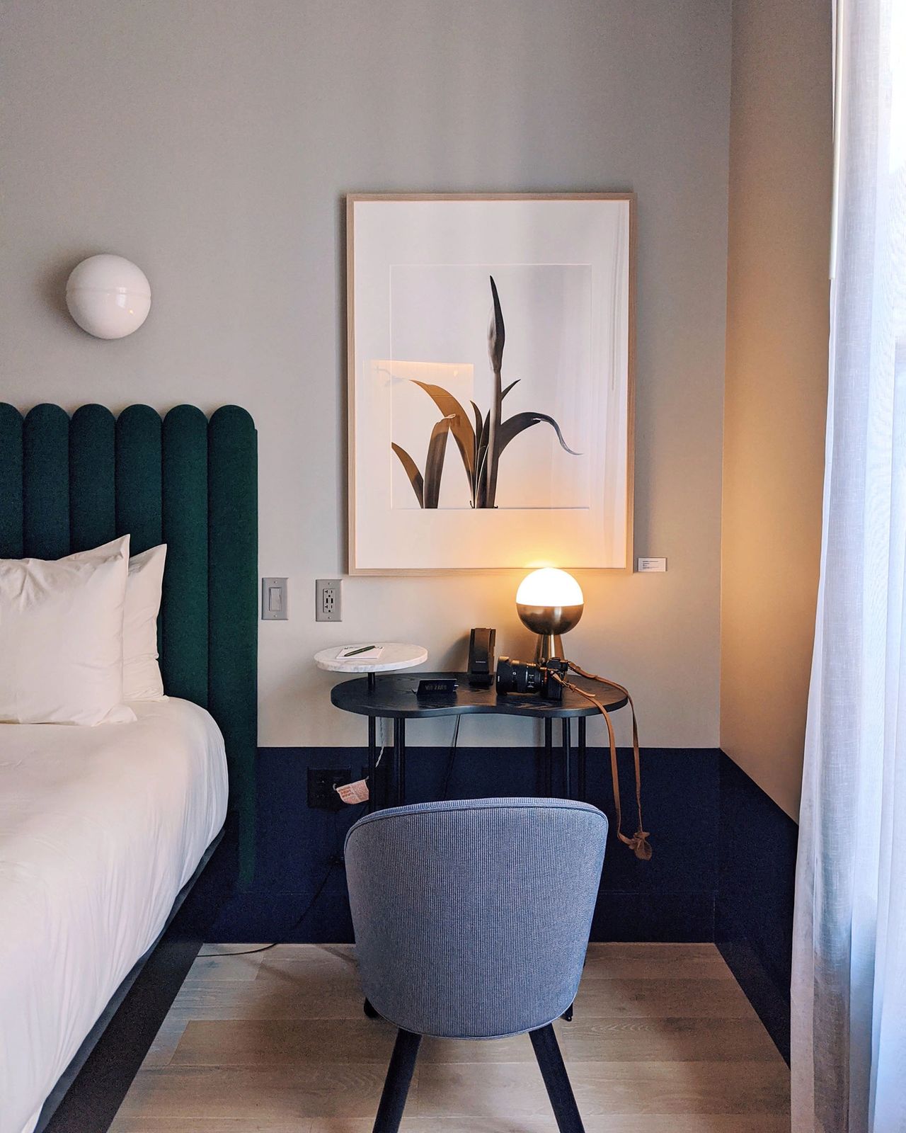 A beautifully styled room at the Woodlark Hotel in Portland, Oregon, featuring a plush green headboard, minimalist artwork, and a cozy desk setup illuminated by soft natural light. The Woodlark blends mid-century modern design with refined comfort, making it one of the best boutique hotels in downtown Portland for design lovers and creative travelers.
