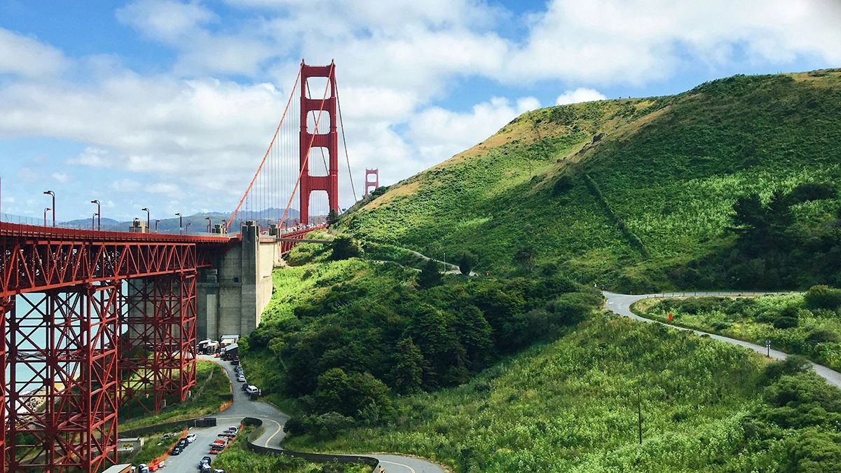 Golden Gate Bridge viewed from Battery Spencer with lush green hills and winding roads in San Francisco.