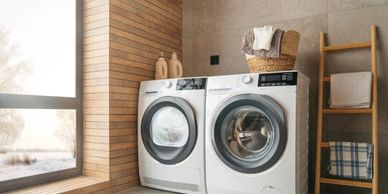 Modern laundry room with washer, dryer, and wooden accents.