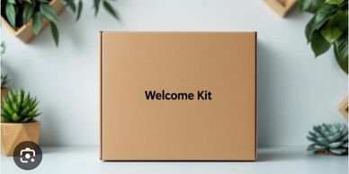 A brown box labeled 'Welcome Kit' surrounded by small potted plants.