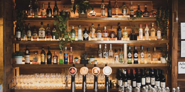 Bar shelves with liquor bottles and glassware under warm lighting.