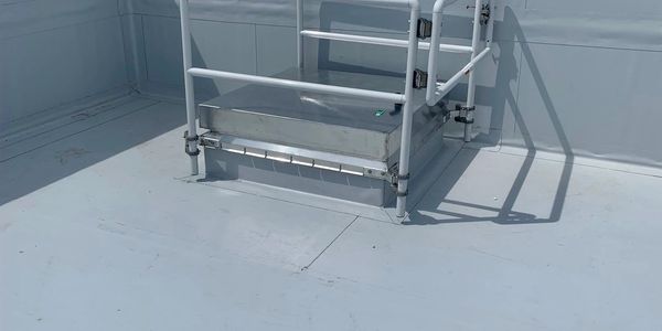 Metal rooftop hatch with railing on a flat roof.