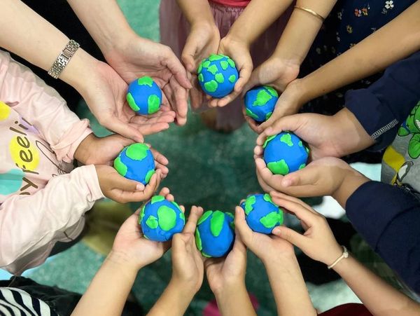 Multiple hands holding small Earth models in a circle.
