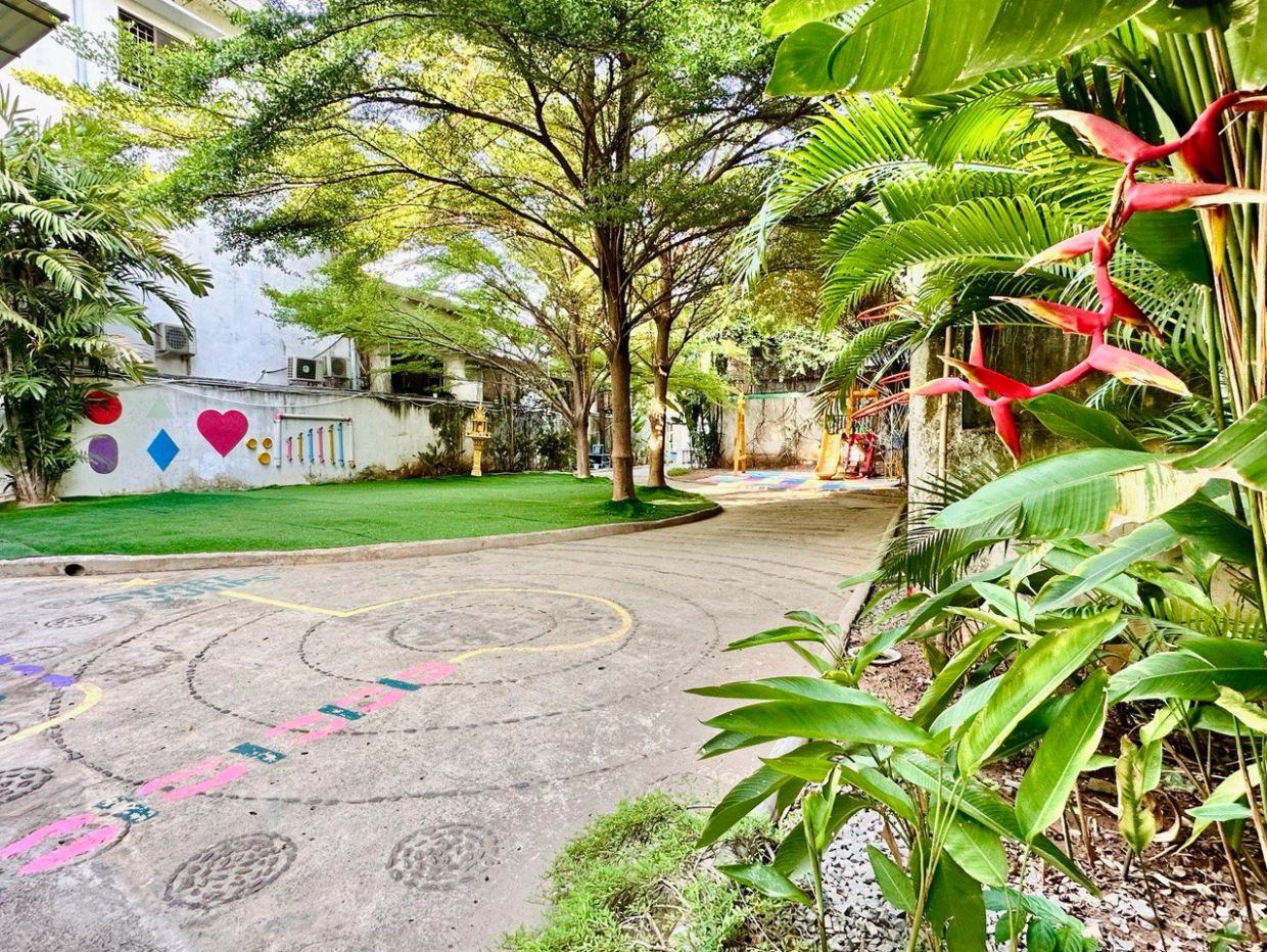 A vibrant outdoor playground with greenery and colorful wall art.