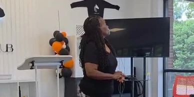 Woman speaking at an indoor event near a podium.