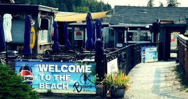 Outdoor beachside bar with welcome signs and umbrellas.