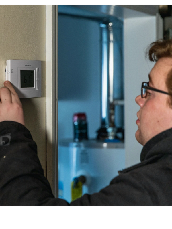A technician making routine maintenance, repair inspection of a thermostat in Wyandotte Michigan