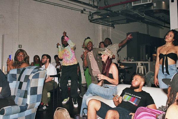 A lively group of friends enjoying a casual indoor party with music and dancing.
