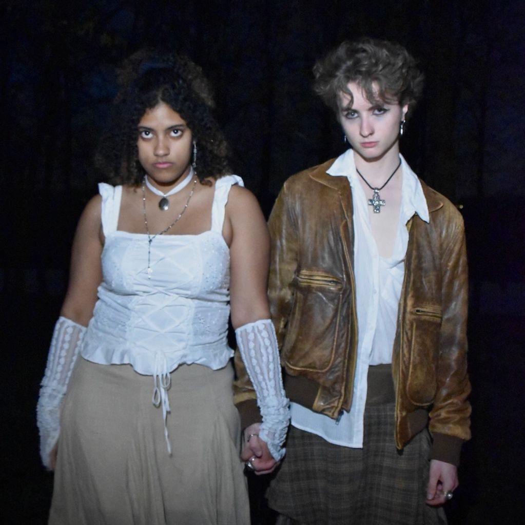 Two people holding hands with intense expressions at night.