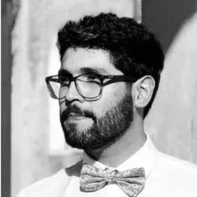 Black and white portrait of a bearded man wearing glasses and a bow tie.