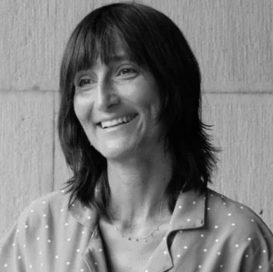 Smiling woman with shoulder-length hair in a polka dot blouse.