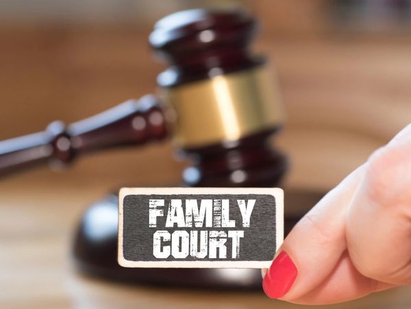 image shows family court sign held betwen woman's fingers.