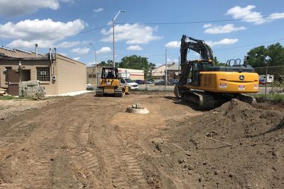 Construction site with heavy machinery and cleared land near a building.